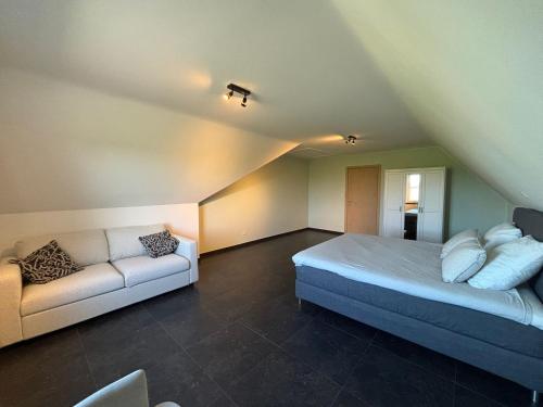 a bedroom with a bed and a couch in a attic at 't Caeneghems Goed in Tielt