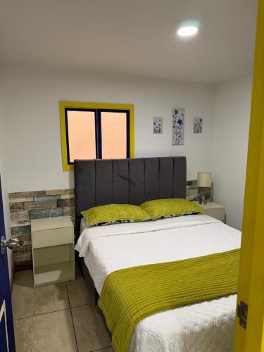a bedroom with a large bed with a yellow blanket at Apartahotel Casa Azul Salento in Salento