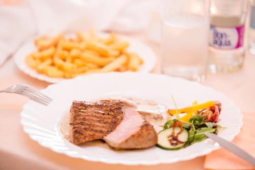 a plate of food with meat and french fries at Hotel&Wellness Knížecí rybník in Tábor
