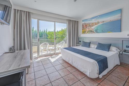 a bedroom with a large bed and a balcony at Hospedium Hotel Abril in San Juan de Alicante