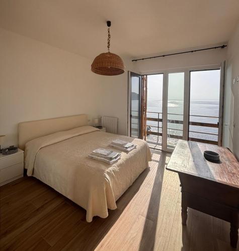 a bedroom with a bed and a table and a balcony at M'illumino d'immenso - MONEGLIA APARTMENTS in Moneglia