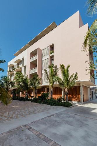 a building with palm trees in front of it at Hola Donceles Suites in Cancún