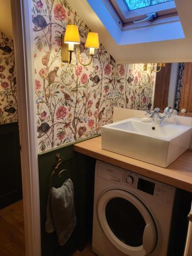 a bathroom with a sink and a washing machine at Freshwater Barn in Benenden