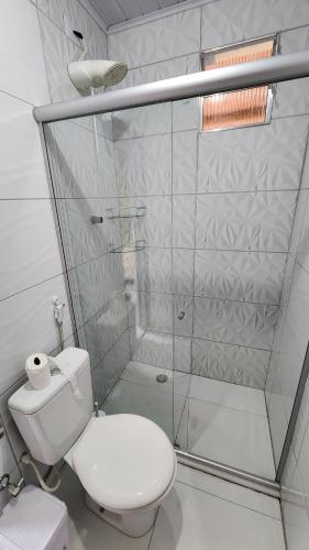 a white bathroom with a shower and a toilet at Suíte Conforto - Leve, Prático e Acolhedor in Itacaré