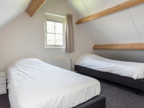 2 camas en una habitación con paredes blancas y ventana en Comfortable home with a terrace 50 m. from the Oosterschelde, en Wemeldinge