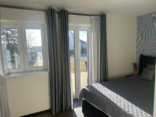 a bedroom with a bed and two windows at Villa Kehrwieder Göhren in Göhren