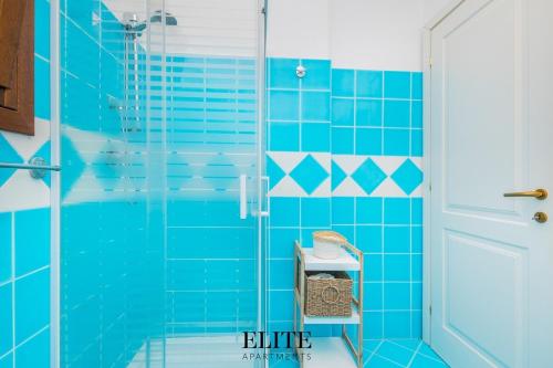 a blue tiled bathroom with a glass shower at Elite Collection Domo Mea Private Pool in Olbia