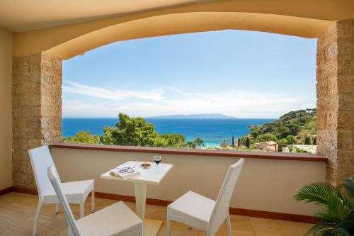 a balcony with a table and chairs and a view of the ocean at Hotel L'Arenella in Giglio Porto