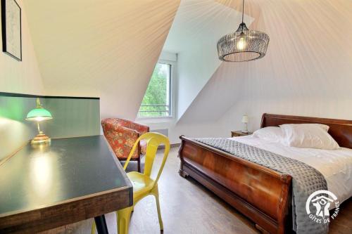 a bedroom with a bed and a desk and a chair at La maison de chris in Theix