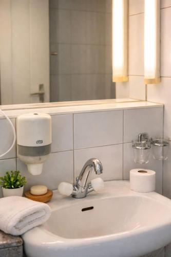 a bathroom with a sink and a mirror at Hôtel La Croisée Neuchâtel in Malvilliers
