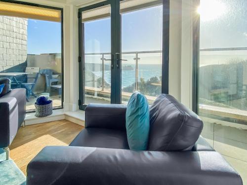 a living room with a couch with a view of the ocean at Cove View Apartment in Porthcurno