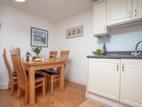 a kitchen with a wooden table with chairs and a sink at Cove View Apartment in Porthcurno
