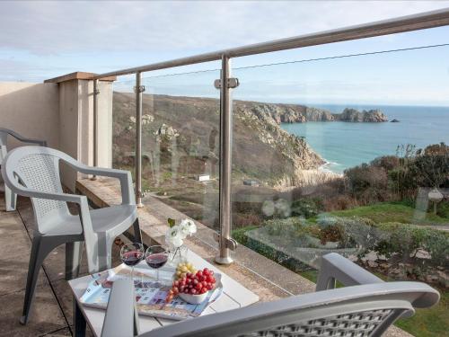 a table and chairs on a balcony with a view of the ocean at Cove View Apartment in Porthcurno