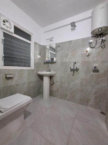 a bathroom with a toilet and a sink at Tenzin's Inn in Jālāpahār