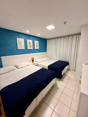 two beds in a room with blue and white at Marulhos Resort in Porto De Galinhas