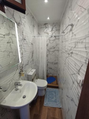 a white bathroom with a sink and a toilet at Αίγλη Apartment in Ierissos