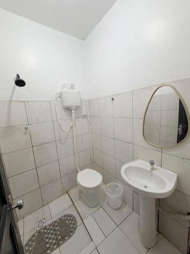 a bathroom with a sink and a toilet and a mirror at Quarto no centro in Manaus
