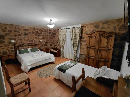 a bedroom with two beds and a table and chairs at Hotel Rural La Posada de Lía in Berzocana