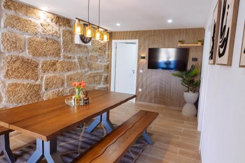 a dining room with a wooden table and a stone wall at Casa da Ti Mília in Trancoso
