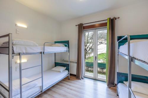 a room with two bunk beds and a window at HI Lousã – Pousada de Juventude in Lousã