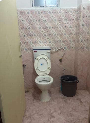 a bathroom with a toilet and a trash can at Jinkos Homestay with self cooking facility in Itānagar