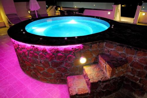 a hot tub in a room with a stone wall at Orfeas Apartments in Kamari