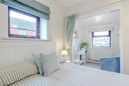 a white bedroom with a bed and a window at Crossways Cottage, Dog-Friendly Cottage Near the Beach in Winterton-on-Sea