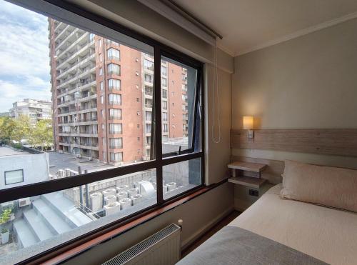 a bedroom with a bed and a large window at Apart Hotel Cambiaso in Santiago