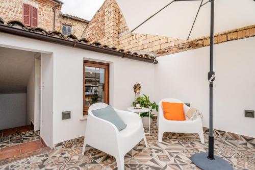 a patio with two chairs and an umbrella at Casa GAH Ripatransone Suite nel Borgo tra Mare e Calanchi in Ripatransone