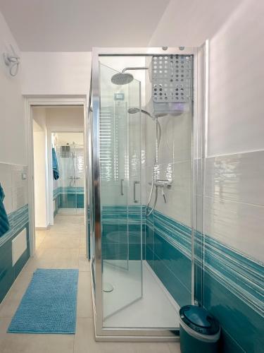 a glass shower in a bathroom with blue tiles at Casa Ammos in Platamona