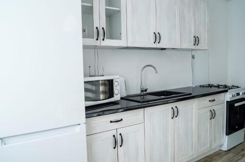 a kitchen with white cabinets and a sink and a microwave at Przystań Baseny in Nowogród Bobrzański