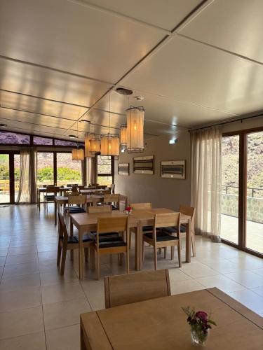 a dining room with tables and chairs and windows at Hostería Varvarco in Varvarco