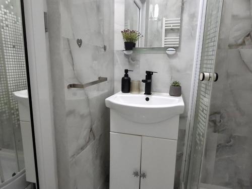 a white bathroom with a sink and a shower at Dani Cute in Vaslui