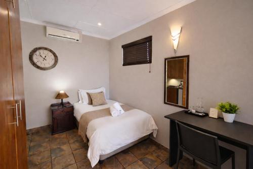 a bedroom with two beds and a clock on the wall at Caesars Place Guest House in Kathu