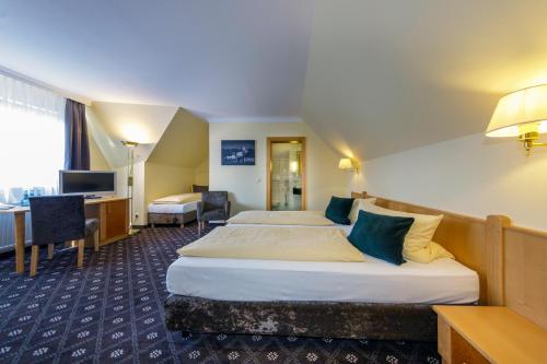 a hotel room with two beds and a desk at Hotel Zum Adler in Nidderau