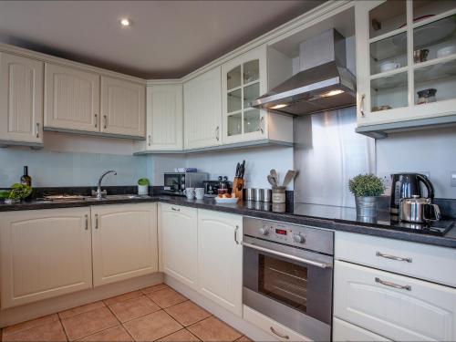 a kitchen with white cabinets and a stove top oven at Cove View Apartment in Porthcurno