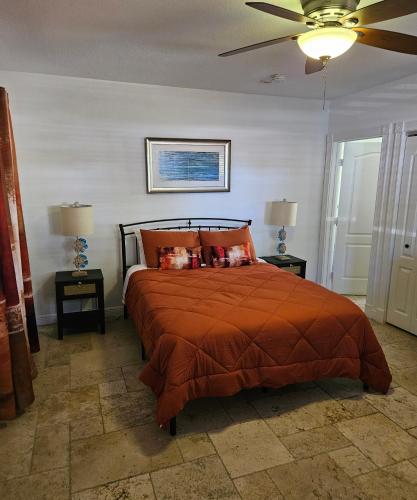 a bedroom with a bed with orange pillows and a ceiling fan at Blue Heron Bridge Hotel and Dive Club in Riviera Beach