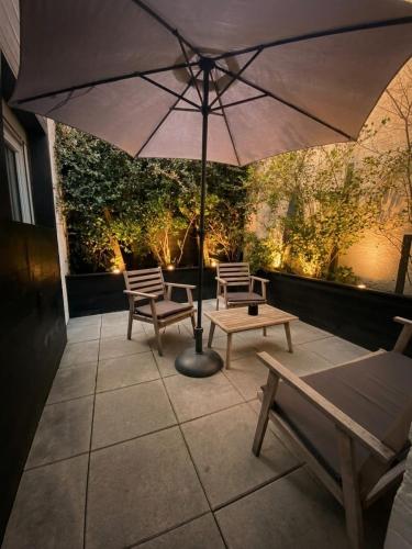a patio with two chairs and an umbrella at CK Suite & Spa - Jacuzzi Privatif - Reims in Reims