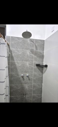 a bathroom with a shower with a tile wall at Furahi Apartment in Mombasa