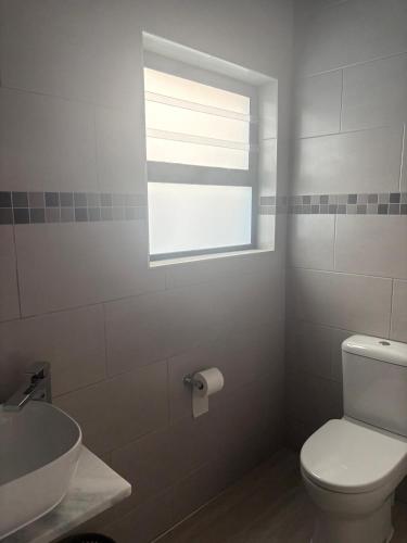 a bathroom with a toilet and a sink and a window at House Stillmar in Walvis Bay