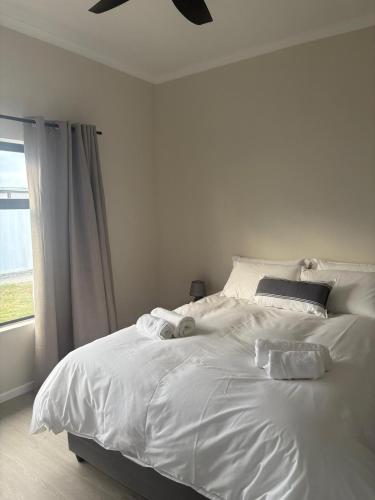 a bedroom with a white bed with two stuffed animals on it at House Stillmar in Walvis Bay