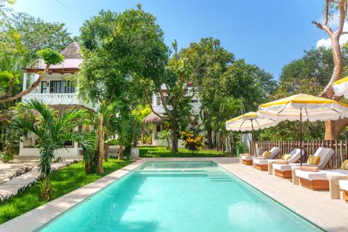 a pool with chairs and umbrellas next to a house at Mikasa Bacalar Hotel Boutique, Lagoon Front in Bacalar