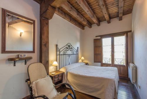 a bedroom with a bed and a chair and a window at LA DEHESILLA in Madriguera