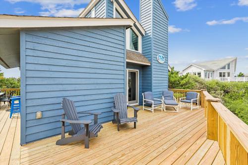 a blue house with chairs on a wooden deck at 3979 - Wright by the Coast in Duck