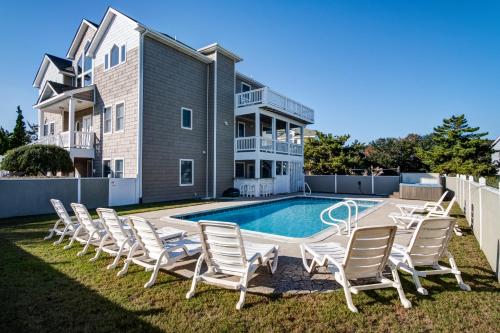 a villa with a swimming pool and lounge chairs at 4052 - Mirth N Mist II in Duck