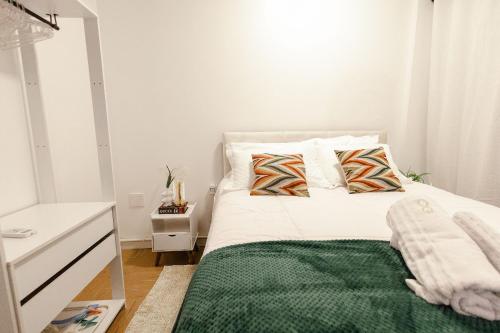 a bedroom with a bed with a green blanket at P&G Apto 202-San Gimignano in Caxias do Sul