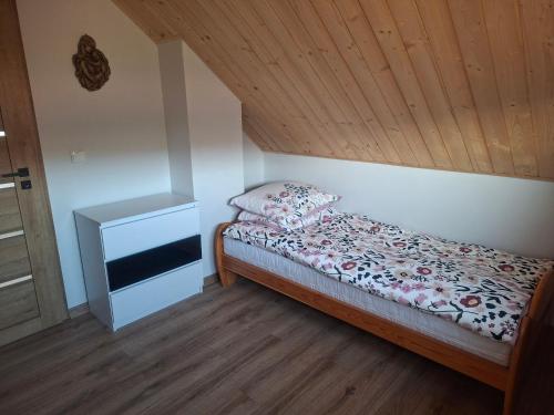 a small bedroom with a bed and a wooden ceiling at Domek na Podgrabiu in Łącko