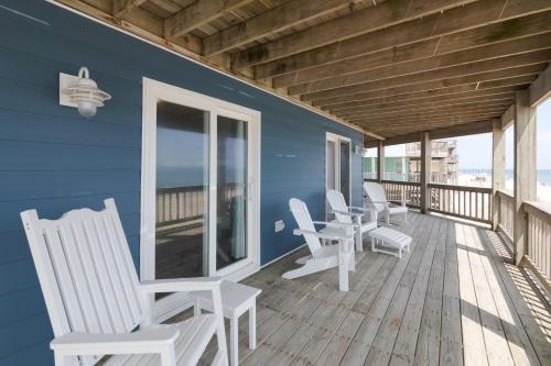 a blue house with white chairs on a deck at 7048 - Tide Song in Rodanthe