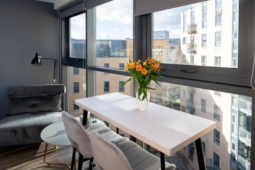 a vase of flowers on a table in a room with a window at Deluxe City Centre Studio Apartment with Balcony & City Views - FREE WIFI NETFLIX, GYM ACCESS - WESTONE in Sheffield