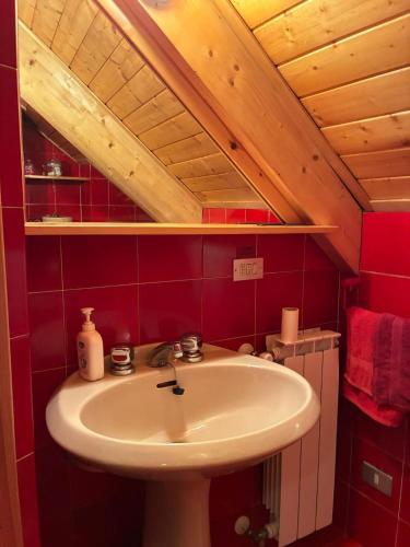 a bathroom with a sink and a red wall at La mansarda in Santa Maria Maggiore